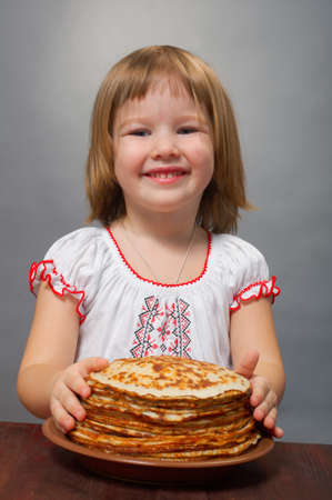 Russian little girl eats pancakes with red caviar.の写真素材
