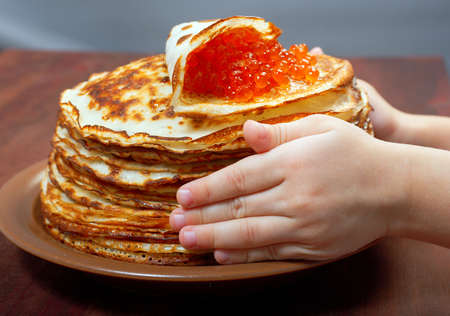 Traditional Russian pancakes  with red caviar.hands childの写真素材