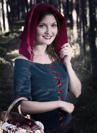 red Riding  hood standing in a wood . beautiful girl in medieval dressの写真素材
