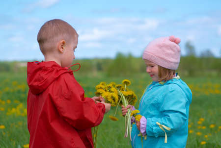 boy and small girl  on meadow with dandelionの写真素材