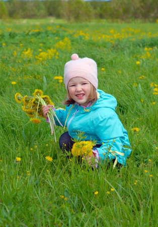 small girl  on meadow with dandelionの写真素材