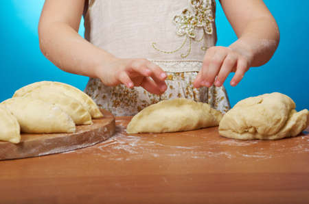 Smiling little girl kneading dough at kitchen .Detail of hands kneading doughの写真素材