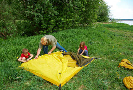happy Father with children installing their tent on camping site. の写真素材