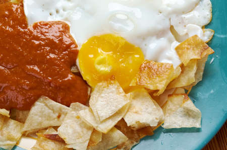 Huevos con chilaquiles -  Mexican traditional breakfast eggs. Eggs with tortilla chips topped with red sauce.の写真素材