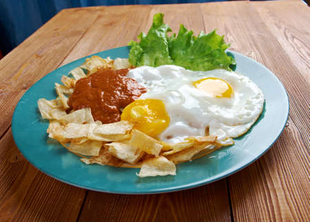 Mexican traditional breakfast eggs. Eggs with tortilla chips topped with red sauce.の写真素材