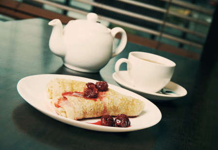 teapot, cup of tea and pancakes on plate with sweet cherry confitureの写真素材