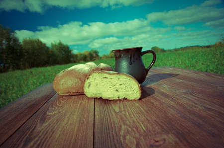 Homemade bread and mug milk on a wooden table.の写真素材