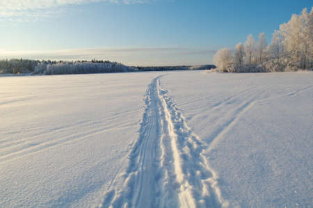 Winter landscape.trace of a snowmobile on frozen lakeの写真素材