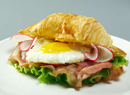 Summer Morning Breakfast Croissant stuffed scrambled eggs and fried baconの写真素材