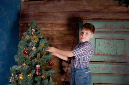 Happy little Boy decorate Christmas tree in beautiful living room with traditional fire place. の写真素材