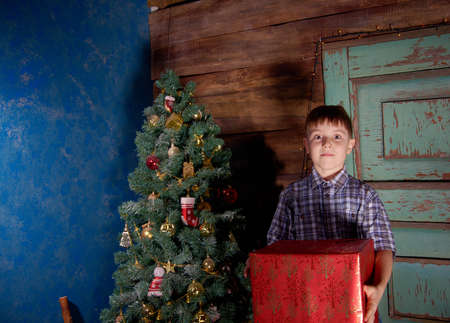 Happy little Boy decorate Christmas tree in beautiful living room with traditional fire place.の写真素材