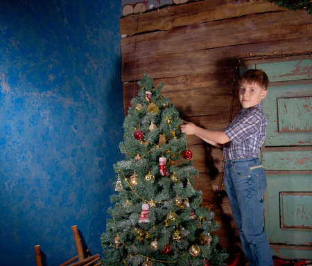 Happy little Boy decorate Christmas tree in beautiful living room with traditional fire place. の写真素材