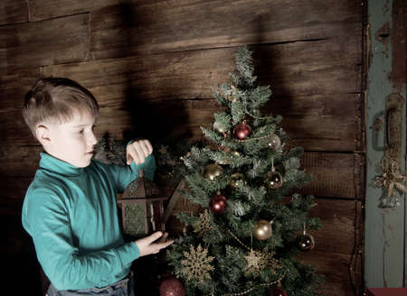 Happy little Boy decorate Christmas tree in beautiful living room with traditional fire place.の写真素材