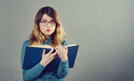 young pretty fair-haired teenage girl in glasses with a thick book ,  lifestyle people concept