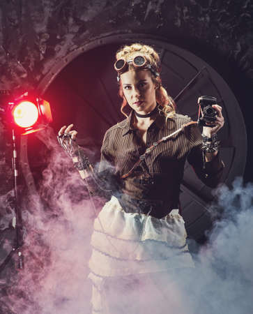 Beautiful steampunk girl in goggles with old camera , model in the style of a steampunk in a beautiful creative studio. Fashion, styleの写真素材
