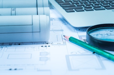 Architectural blueprints and blueprint rolls and a drawing instruments on the work table の写真素材