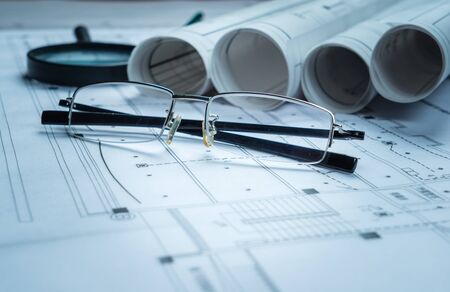 Architectural blueprints, blueprint rolls and a drawing instruments on the worktableの写真素材