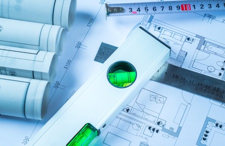 Architectural blueprints, blueprint rolls and a drawing instruments on the worktable