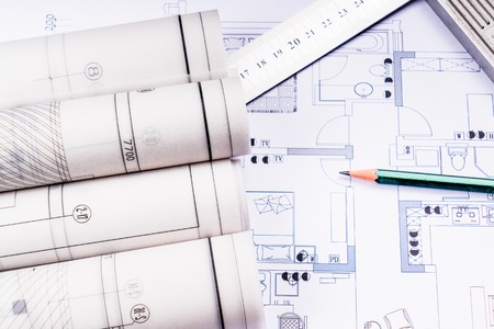 Architectural blueprints, blueprint rolls and a drawing instruments on the worktableの写真素材