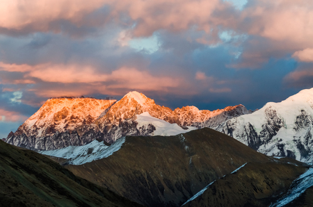 view from St. Moritz in Switzerland: high snow and ice capped alpine mountain range with red illuminated peaks at sunset and the moon outの写真素材