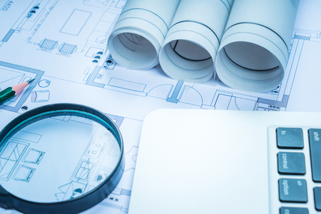 Architectural blueprints, blueprint rolls and a drawing instruments on the worktableの写真素材