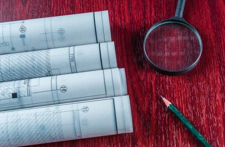 Architectural blueprints, blueprint rolls and a drawing instruments on the worktable