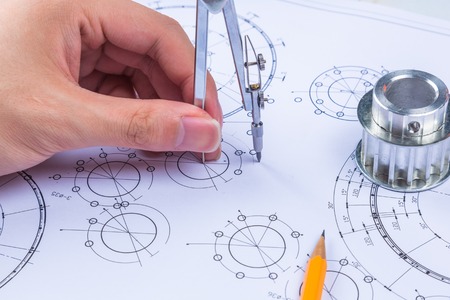 Man's hand with a compass. Mechanical engineer at work. Technical drawings. Pencil, compass,...