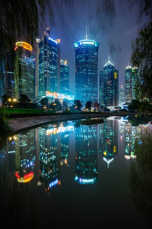 River And Modern Buildings Against Sky at night.の写真素材