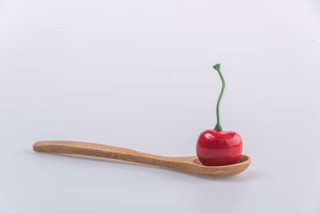 Cherry isolated on wooden spoon on white background.の写真素材