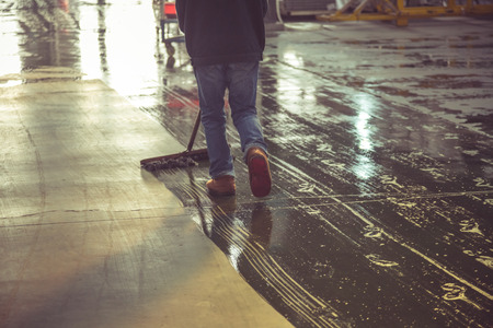 low section of male worker mopping the concrete floor in factory/warehouse,rear view.の写真素材