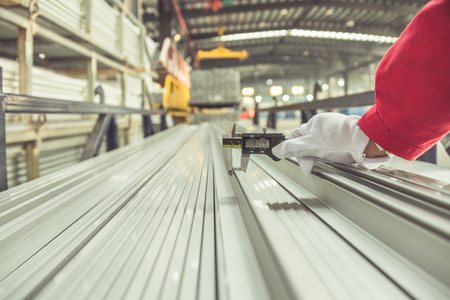 closeup of inspector checking finished pieces of aluminium alloy by using vernier caliper.の写真素材