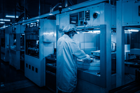 workers and machinery in a solar panel manufacturing industry factory.