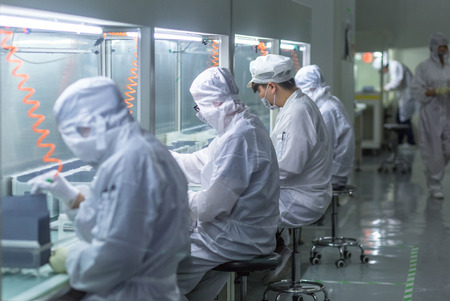 workers and machinery in a solar panel manufacturing industry factory.のeditorial素材