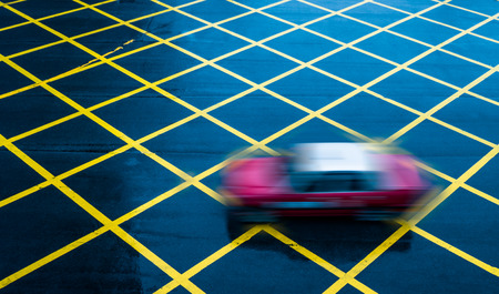 cars driving through yellow no parking area on asphalt street,Hong Kong,china.