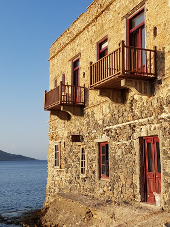 Î two-story stone mansion with red balconies by the sea, on the island of Leros, Greece.の写真素材
