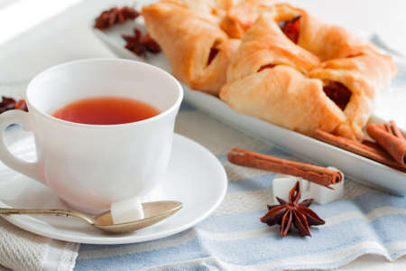 white china cup of black tea with teaspoon cubic sugar and fresh baked pastryの写真素材