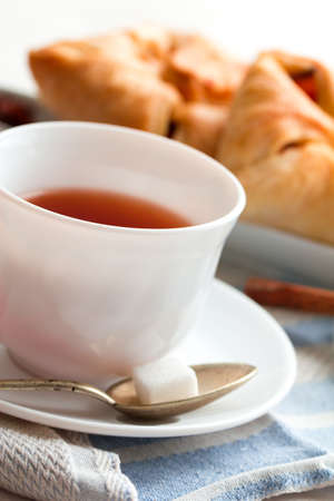 white china cup of black tea with teaspoon cubic sugar and fresh baked pastryの写真素材