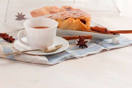 white china cup of black tea with teaspoon cubic sugar and fresh baked pastryの写真素材