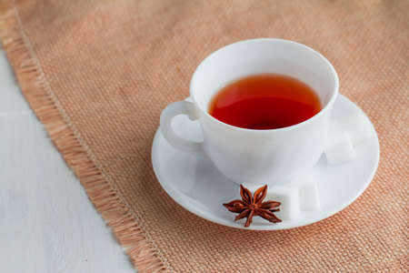 white china cup of black tea with teaspoon and cubic sugar  on canvas tableclothの写真素材
