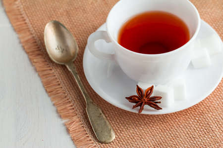 white china cup of black tea with teaspoon and cubic sugar  on canvas tableclothの写真素材