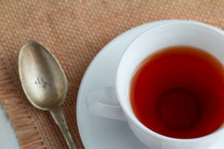 white china cup of black tea with teaspoon and cubic sugar  on canvas tableclothの写真素材