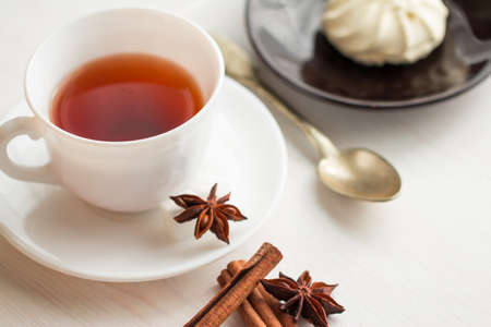 cup of tea with teaspoon, anise and marshmellow on saucerの写真素材