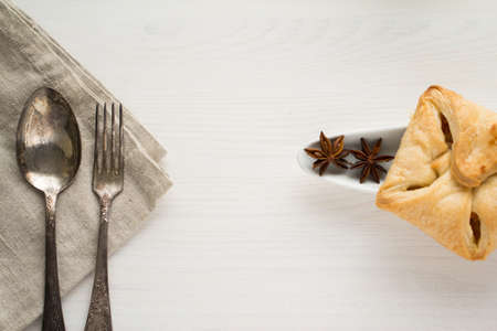 old spoon and fork on grey kitchen towel with sweet pastry and anise star on a white backgroundの写真素材