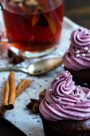 mug of blacktea with chocolate cupcakes covered with berry cream toppingの写真素材