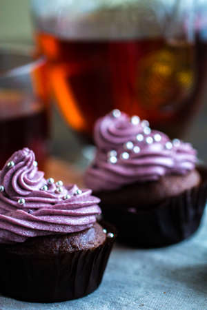 mug of blacktea with chocolate cupcakes covered with berry cream toppingの写真素材