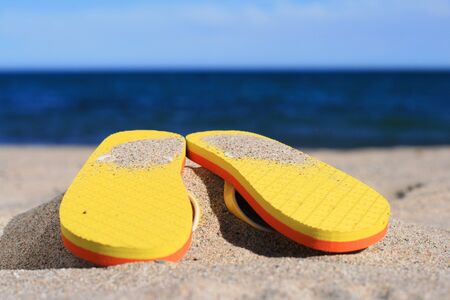 Orange flip-flops in sand on the beach in Barcelona.の写真素材
