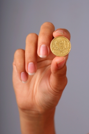 Euro coin in hand over gray background.の写真素材