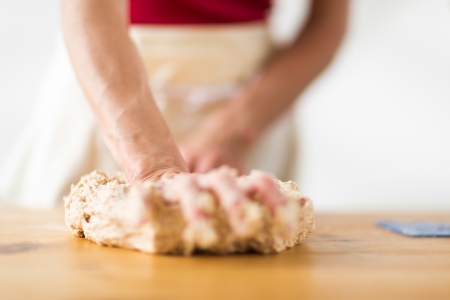 Close-up of the hands of a woman kneading dough on a wooden tableの写真素材