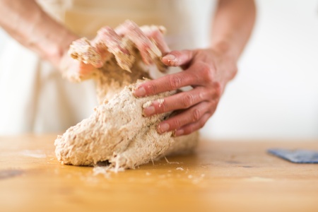 Close-up of the hands of a woman preparing traditional bread on a wooden tableの写真素材