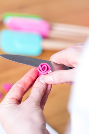 Hands of a young woman making edible sugar or icing roses to decorate a party cakeの写真素材